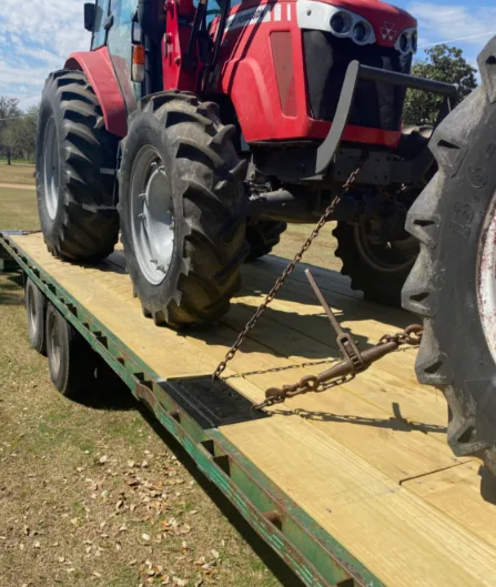 A close-up of a metal chain and padlock secured to an orange industrial structure against a dark, wooden background.