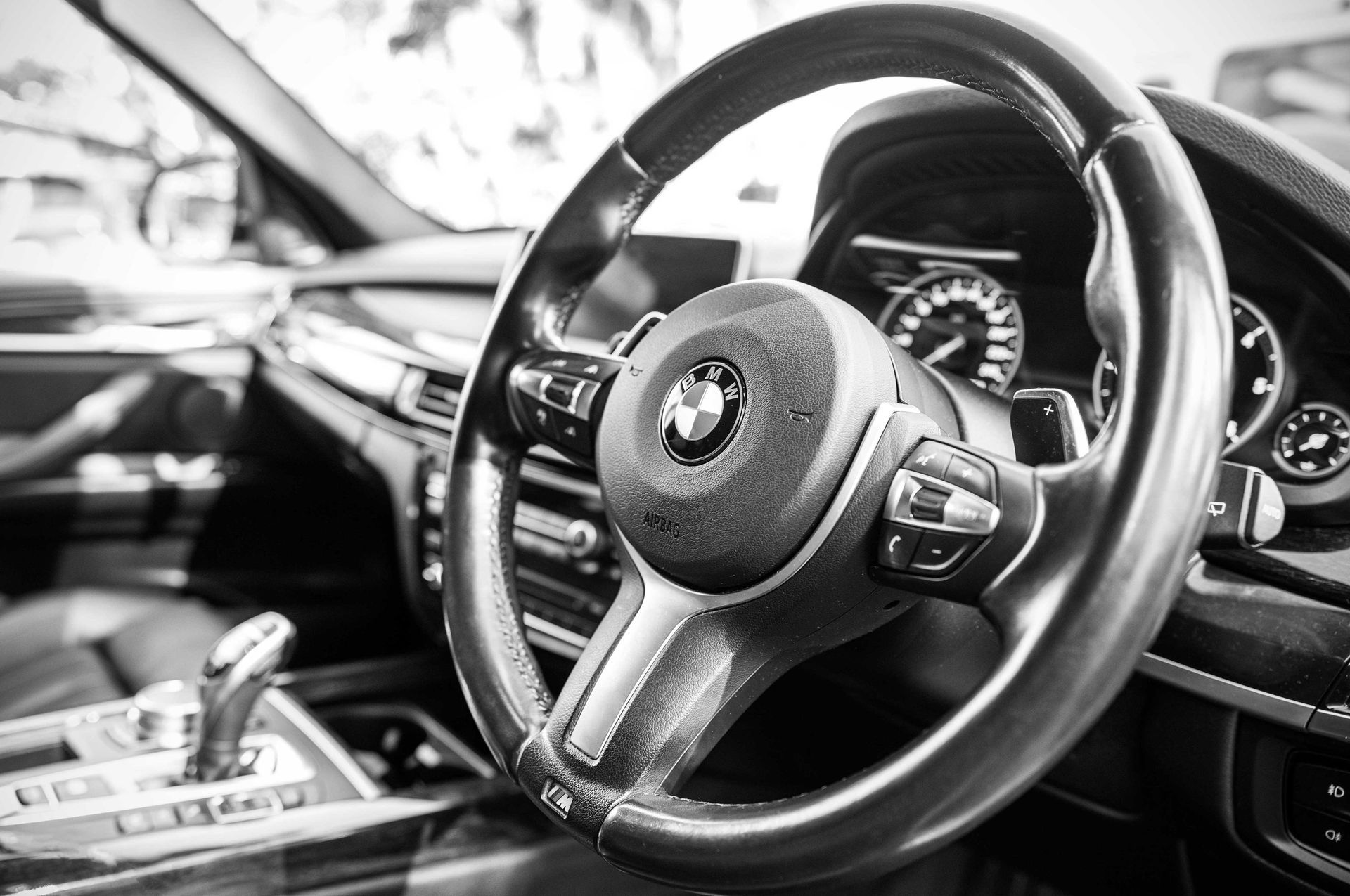 A black and white photo of a steering wheel in a car.