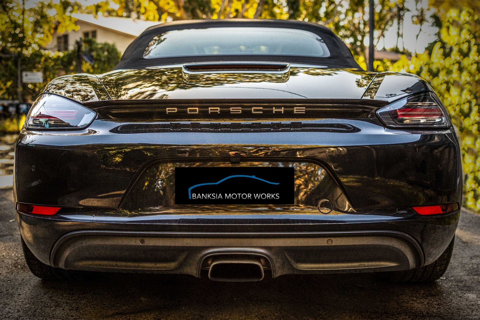 The rear end of a black porsche convertible is shown