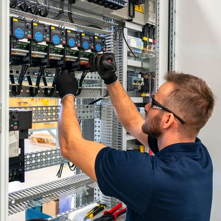 Kevin Walsh Master Electrician | A man in a blue shirt is working on an electrical panel.