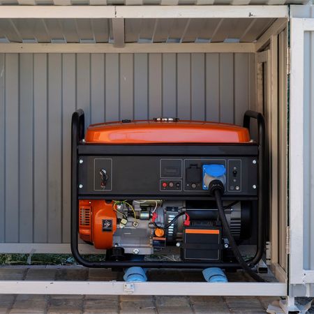 Kevin Walsh Master Electrician | An orange generator is sitting inside of a shed.