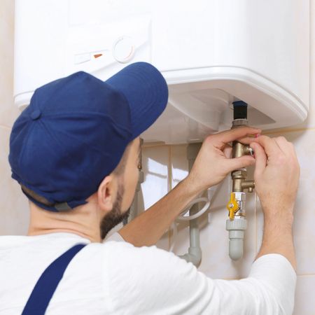 Kevin Walsh Master Electrician | A man in a blue hat is fixing a water heater