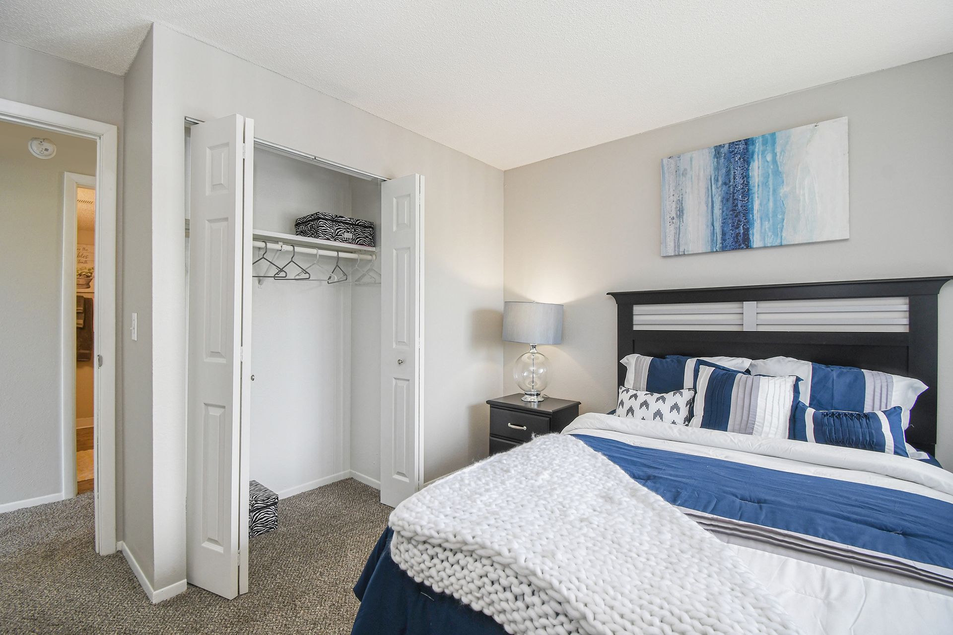 Bedroom with a bed, closet, and nightstand; blue and white color scheme.
