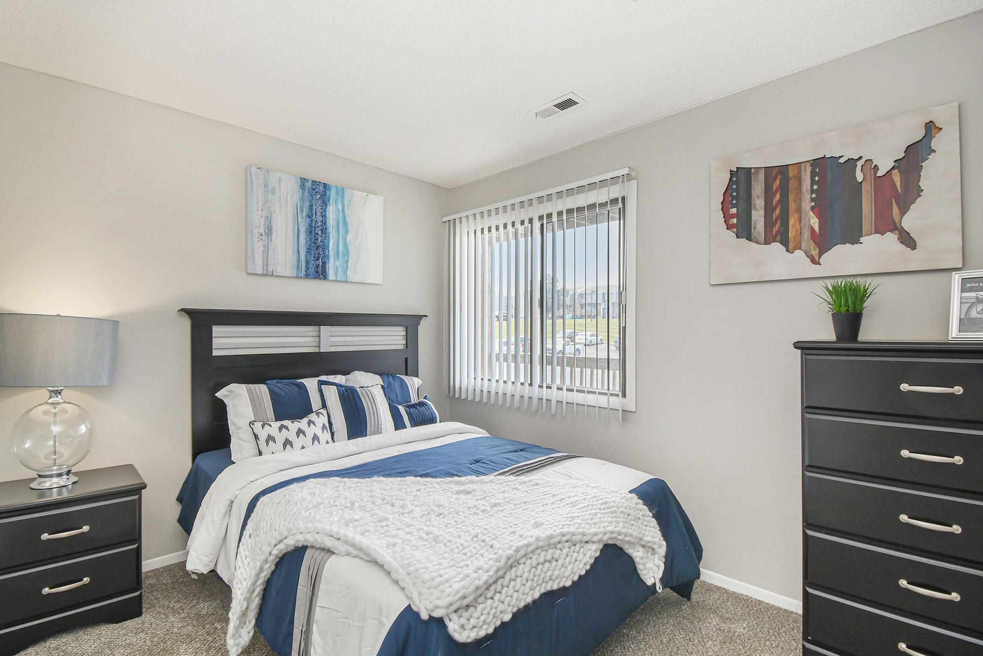 Bedroom with a double bed, dark furniture, blue and white bedding, and art on the walls.
