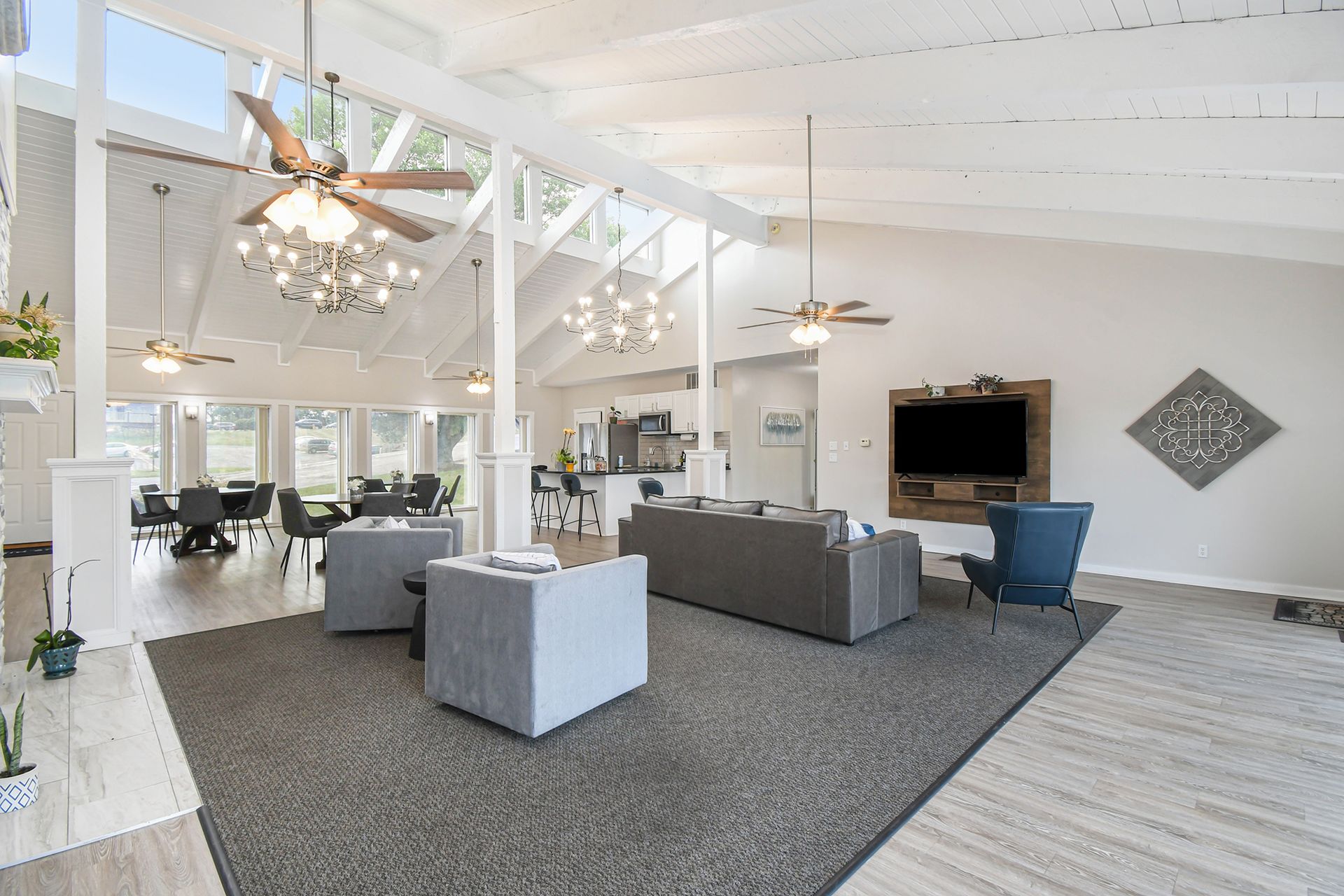 Bright, airy community lounge with vaulted ceilings, seating areas, kitchen, and TV.