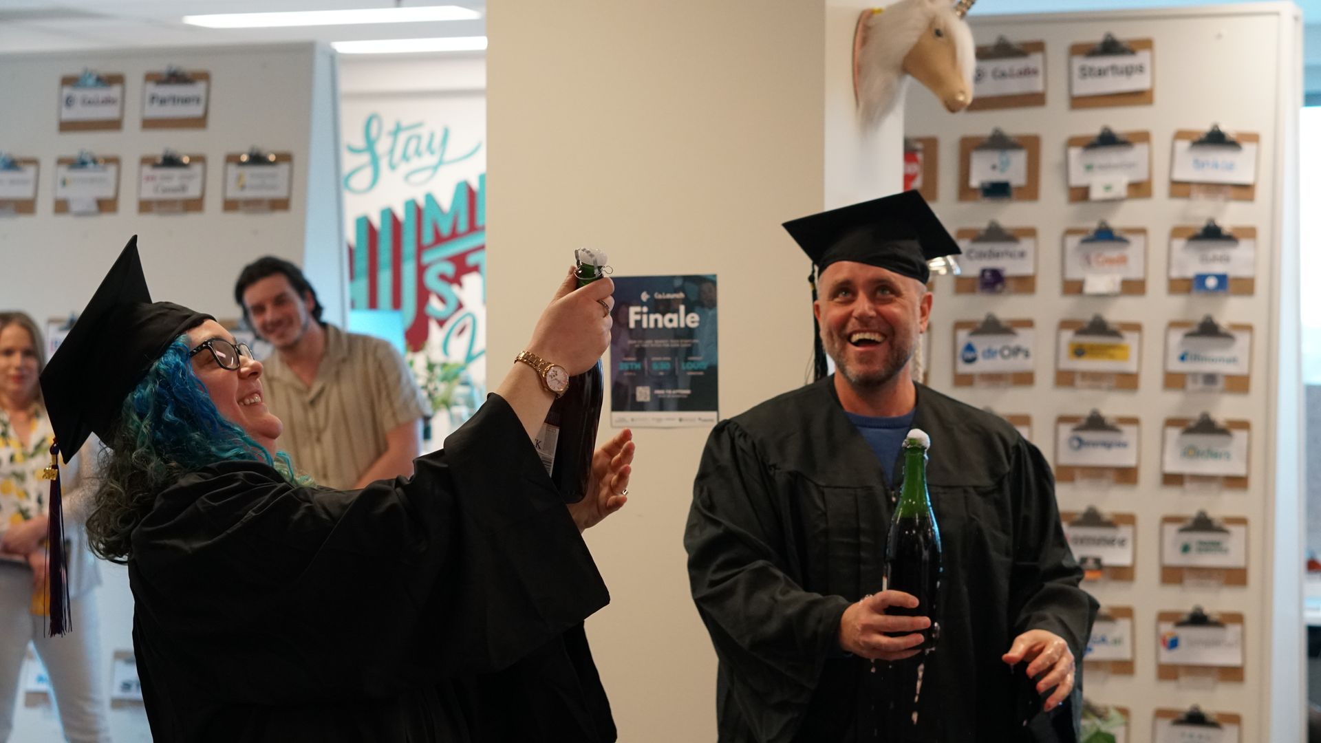 A woman in a graduation cap and gown is taking a picture of a man in a graduation cap and gown.