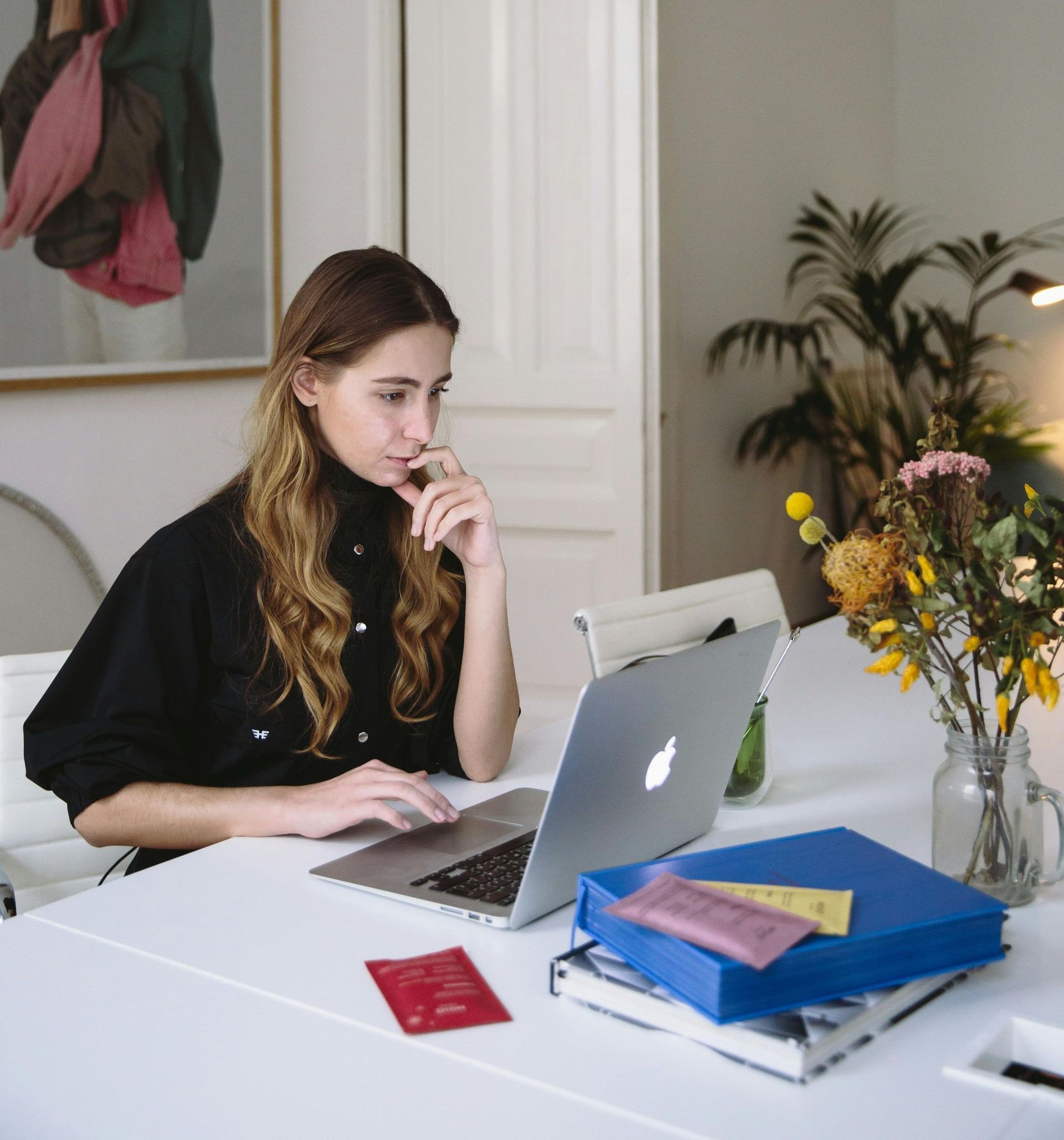 A woman is sitting at a table using an apple laptop