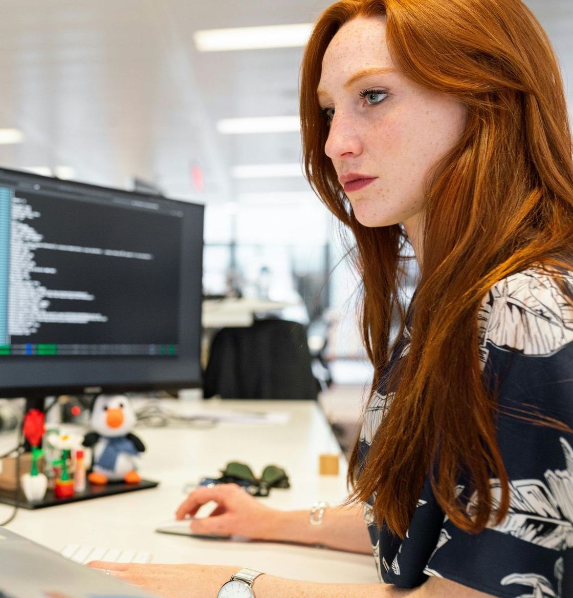 A woman is sitting at a desk looking at a computer screen