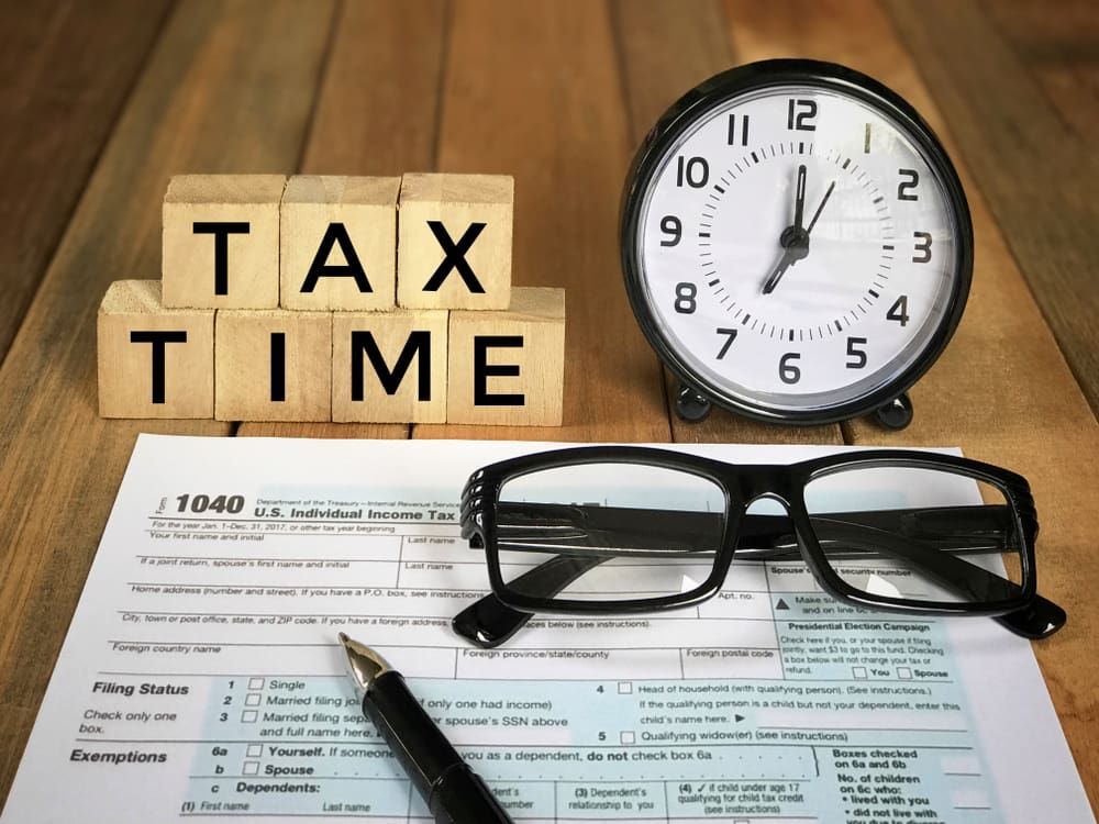 A Clock, Glasses, a Pen and A Tax Form on A Wooden Table — Catalyst Accounting & Tax in The Atherton Tablelands, QLD