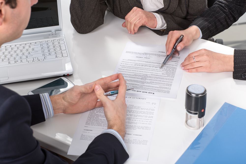 A Group of People Are Sitting at a Table With Papers and a Laptop — Chris Trevor & Associates in Emerald, QLD