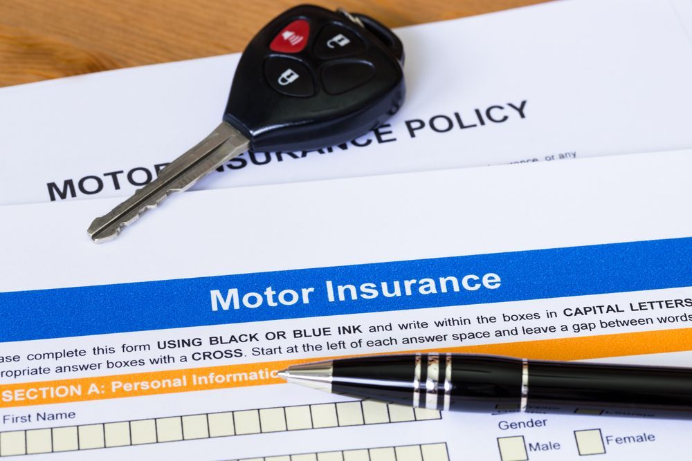 A Car Key Sits on Top of a Motor Insurance Policy — Chris Trevor & Associates in Moranbah, QLD
