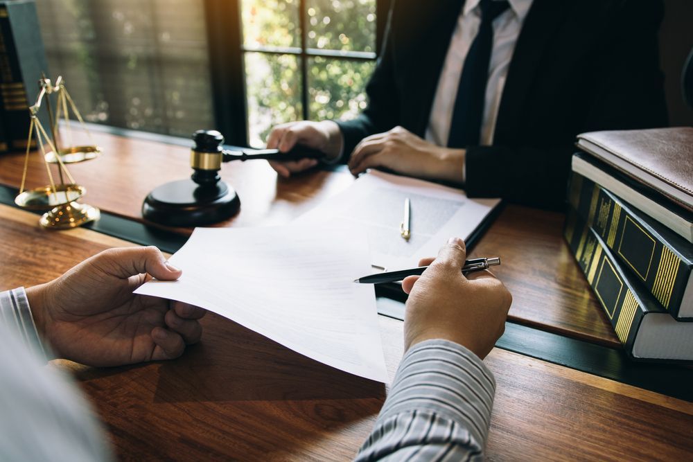 A Man is Holding a Piece of Paper in Front of a Judge — Chris Trevor & Associates in Emerald, QLD