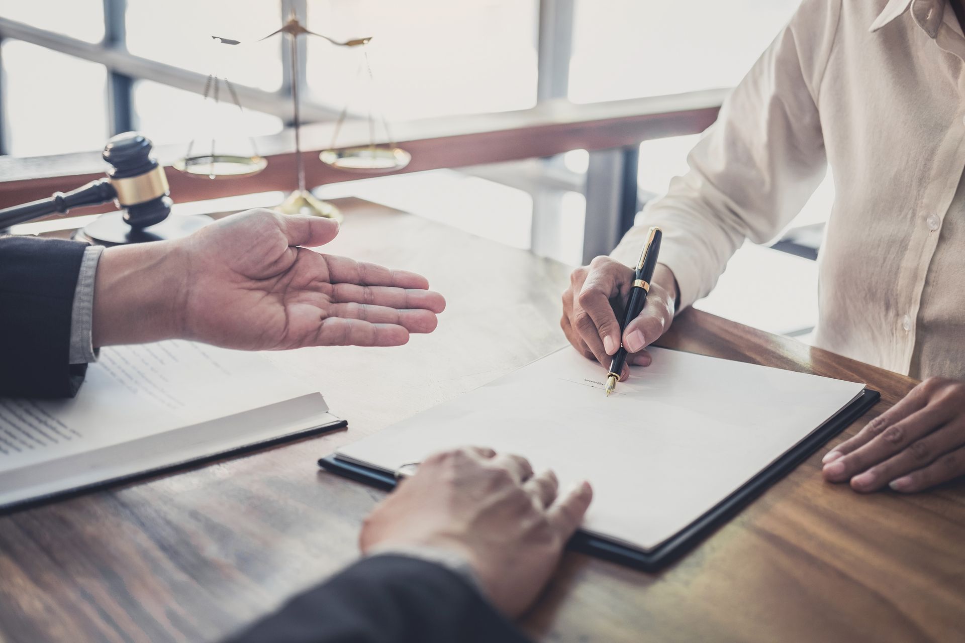 A Man is Giving a Woman a Pen to Sign a Document — Chris Trevor & Associates in Gladstone Central, QLD