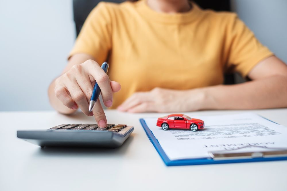 A Woman is Sitting at a Table Using a Calculator and a Pen — Chris Trevor & Associates in Emerald, QLD