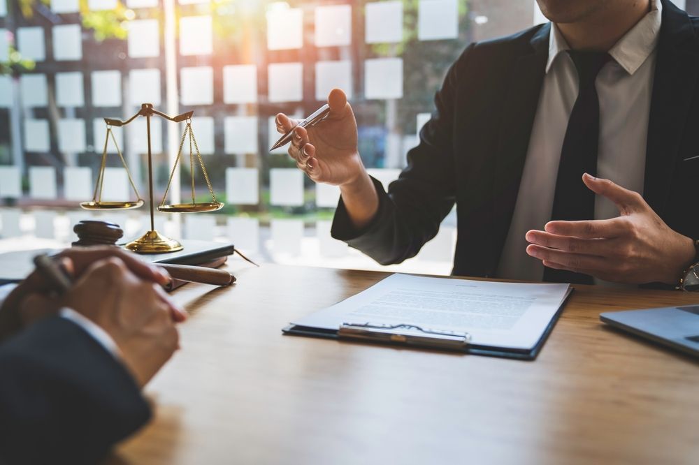 A Man in a Suit and Tie is Sitting at a Table Talking to Another Man — Chris Trevor & Associates in Gladstone Central, QLD