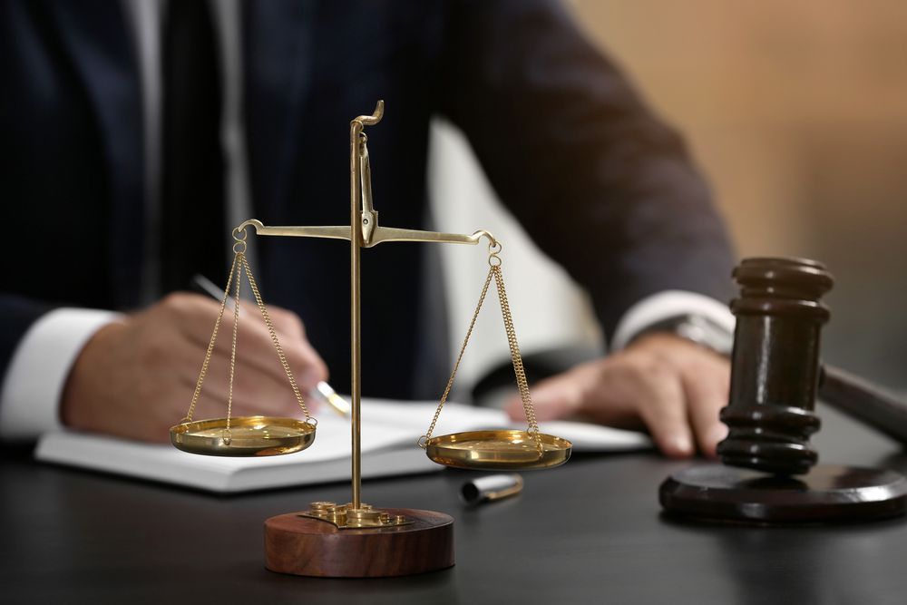 A Judge is Sitting at a Desk With a Scale of Justice and a Gavel — Chris Trevor & Associates in Emerald, QLD
