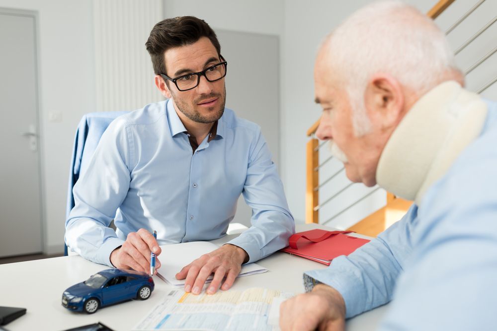 A Man is Talking to an Older Man Who is Wearing a Neck Brace — Chris Trevor & Associates in Rockhampton, QLD