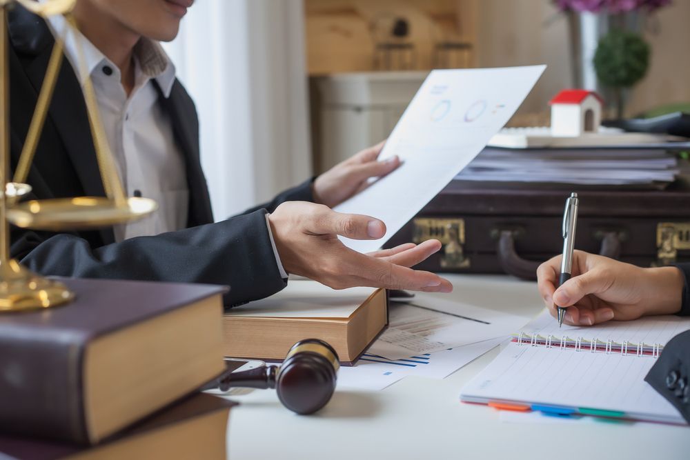 A Man is Giving a Piece of Paper to a Woman Who is Writing in a Notebook — Chris Trevor & Associates in Rockhampton, QLD