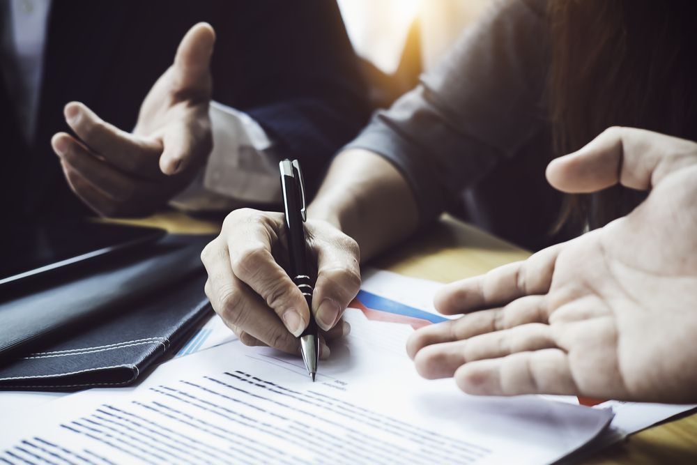 A Person is Writing on a Piece of Paper With a Pen — Chris Trevor & Associates in Clermont, QLD