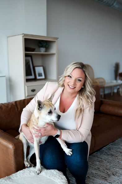 A woman is sitting on a couch holding a dog.