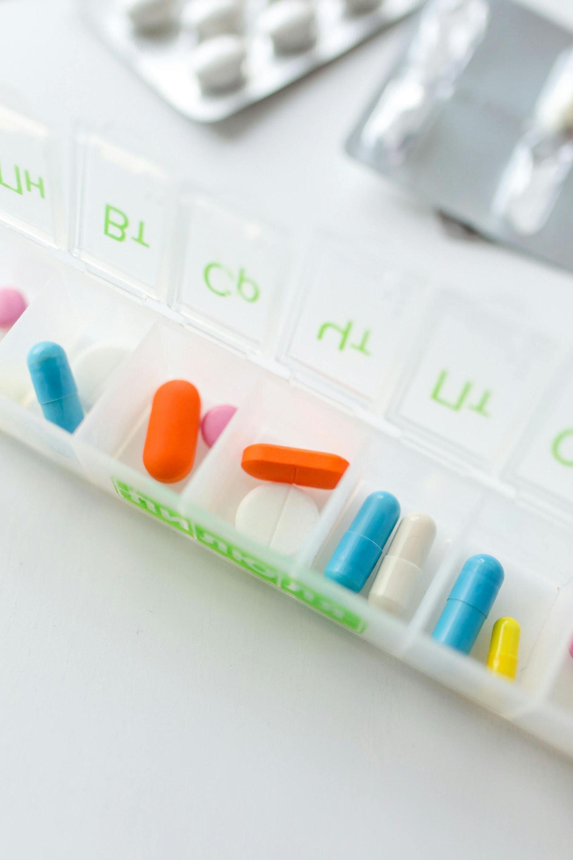 A plastic container filled with different colored pills on a table.