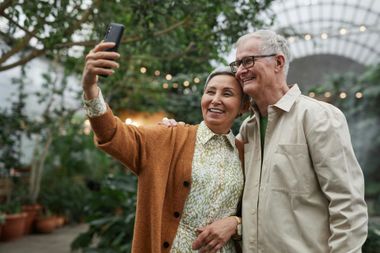 An elderly couple is taking a selfie with a cell phone.