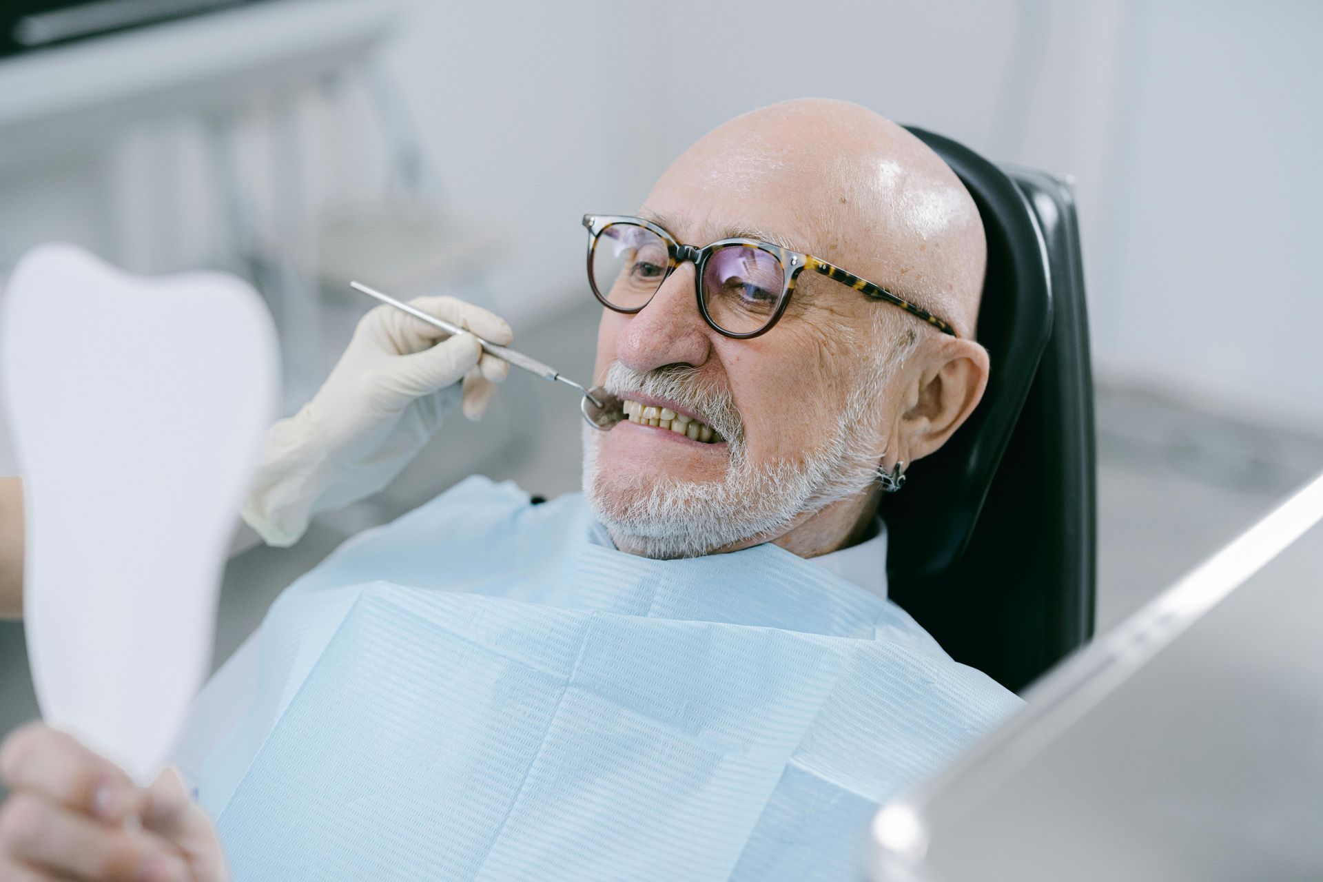 An elderly man is having his teeth examined by a dentist.