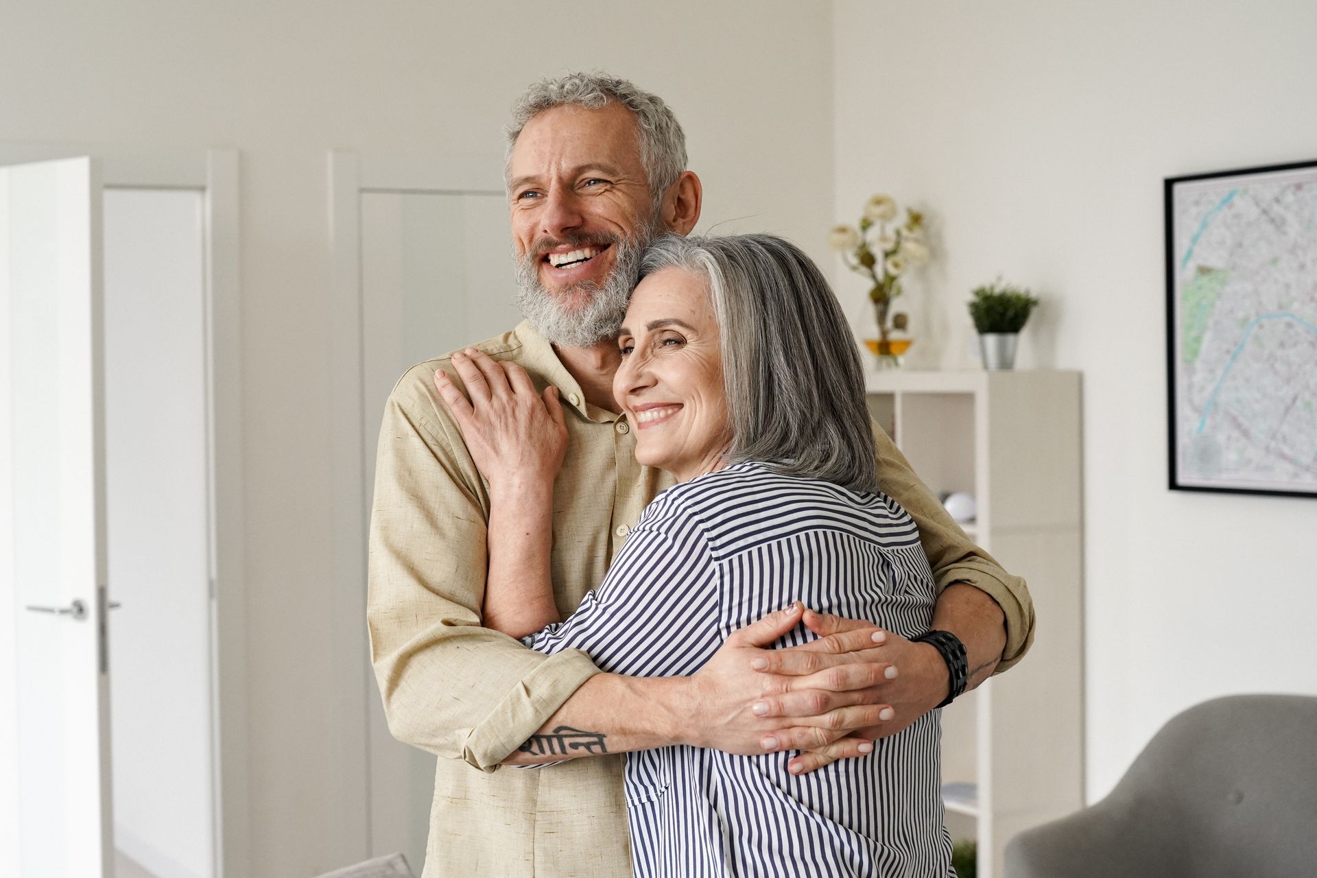 A man and a woman are hugging each other in a living room.