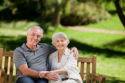 An elderly couple is sitting on a park bench.