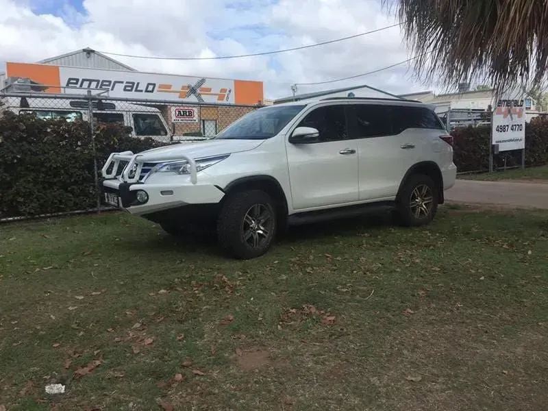 A White Suv is Parked in a Grassy Area in Front of a Building — Emerald 4x4 in Emerald, QLD