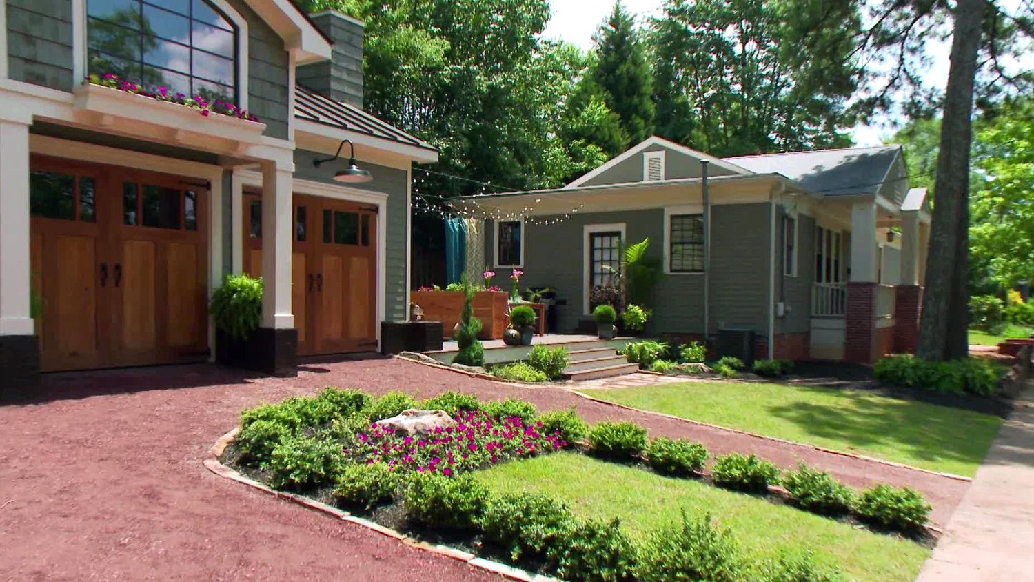 A large house with a garage and a smaller house in the background.