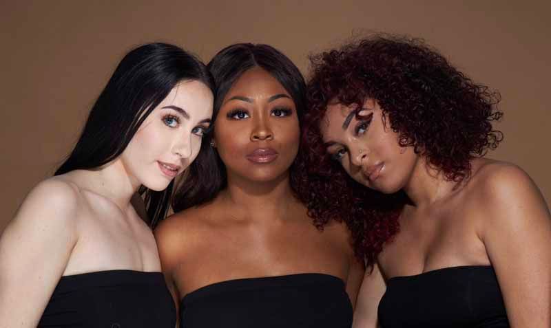 Three women of different races are posing for a picture together.