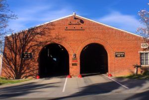 A brick building with two arches and a road going through it.