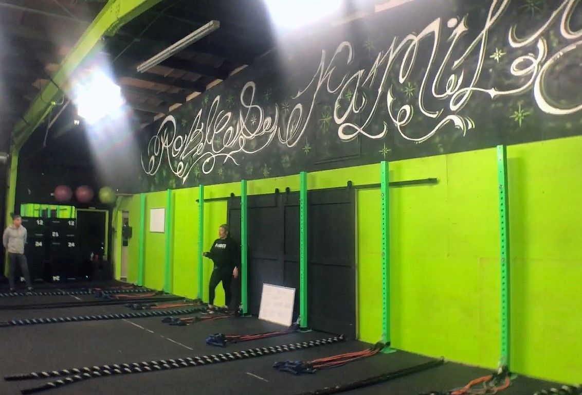 A man is standing in a gym with green walls.