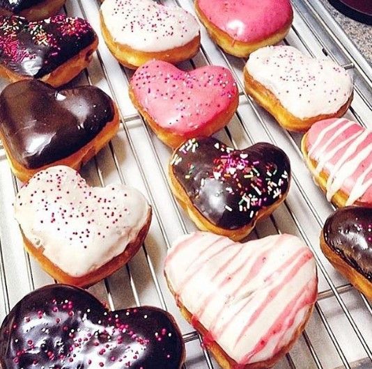 A bunch of heart shaped donuts on a cooling rack