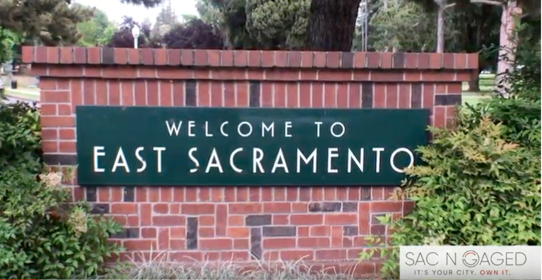 A welcome to east sacramento sign is on a brick wall.