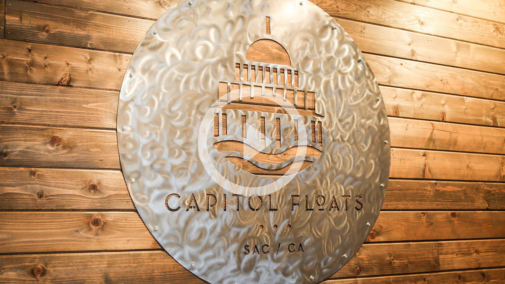 A sign on a wooden wall that says capitol floats