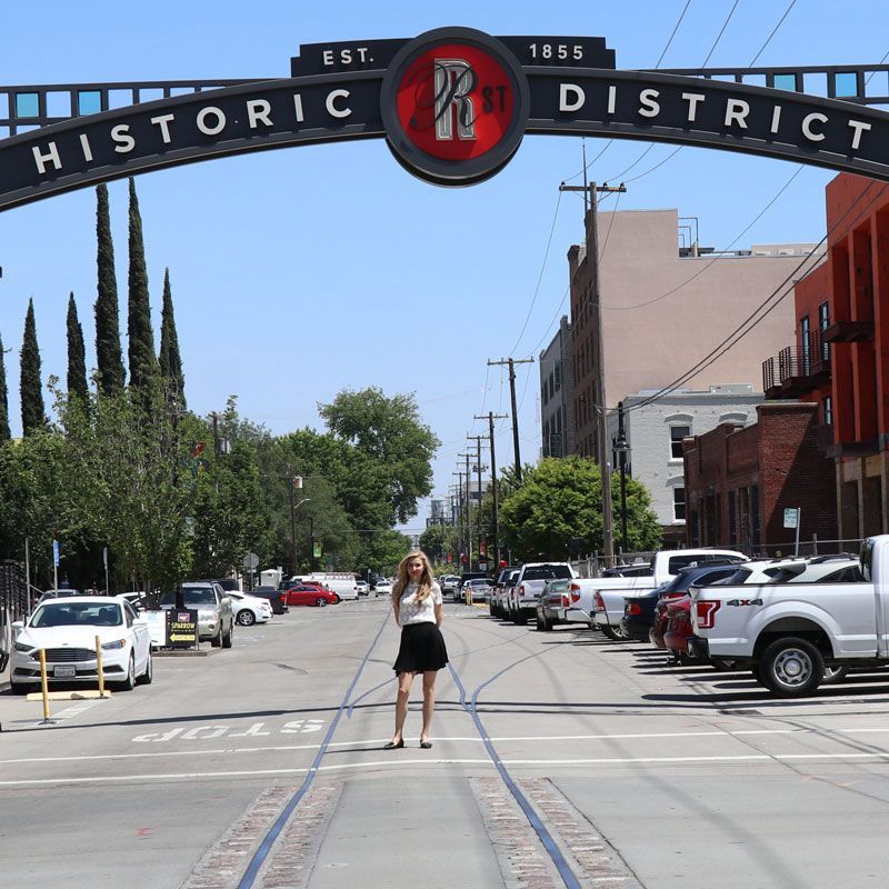 A woman stands in front of a historic district sign
