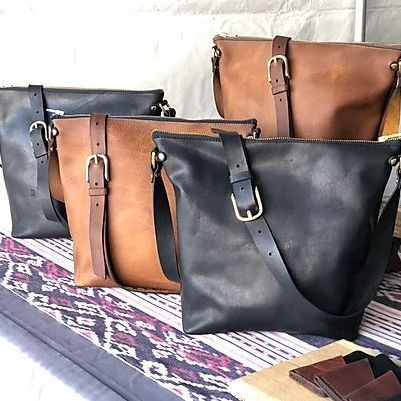 A group of leather bags are sitting on top of each other on a table.