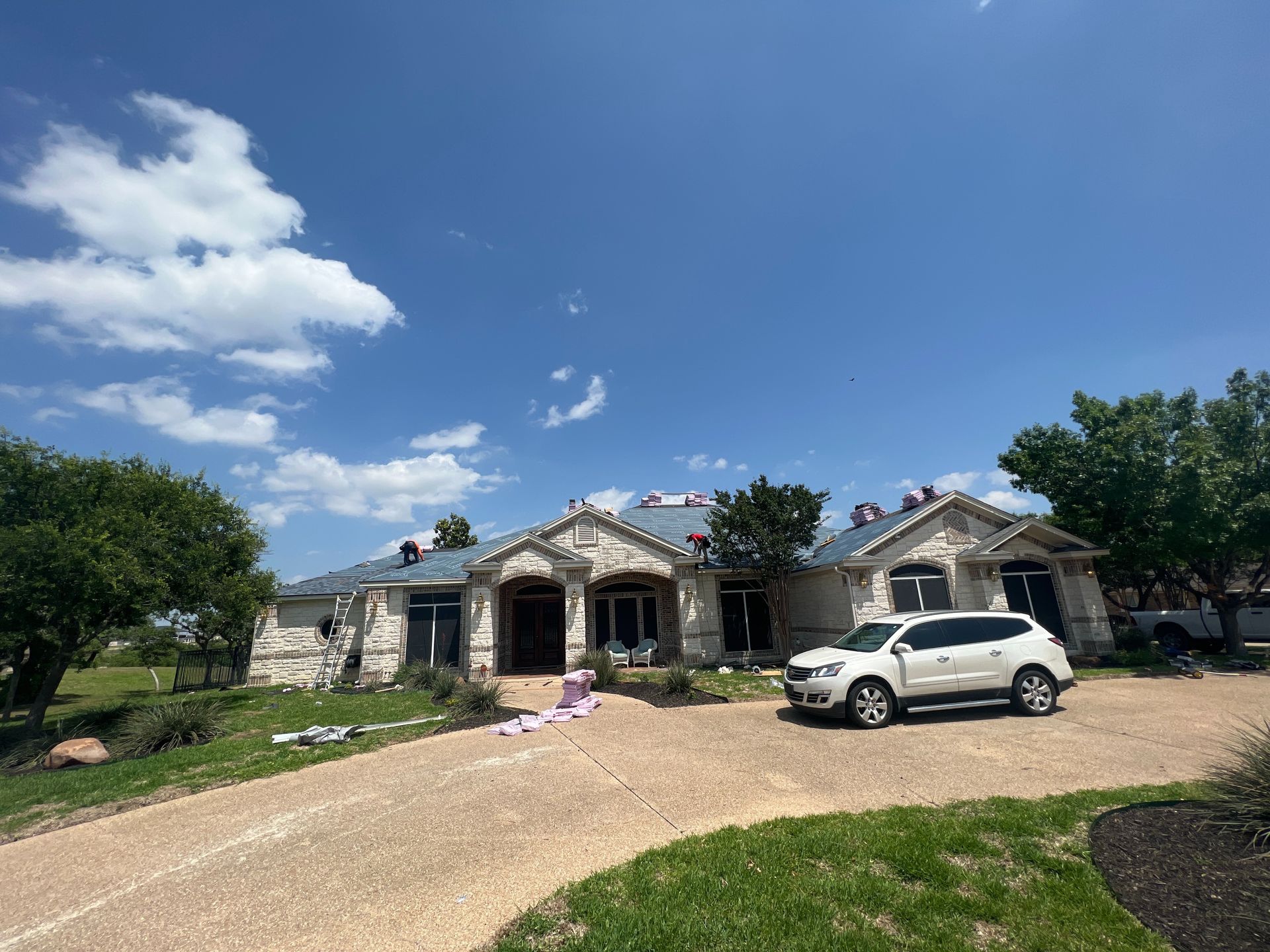 A white suv is parked in front of a large house.