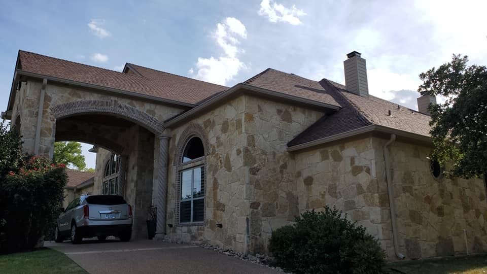A car is parked in front of a large stone house.