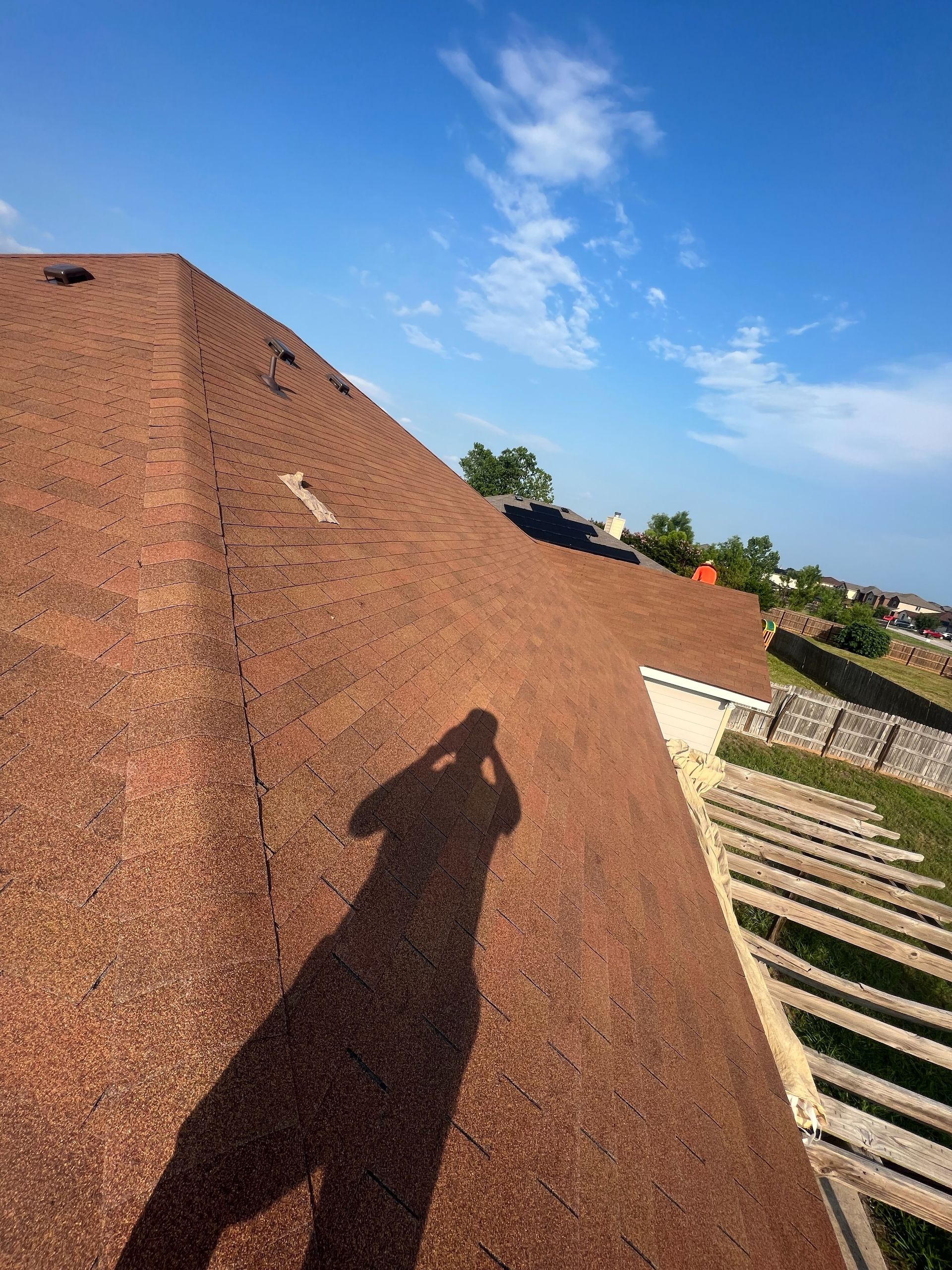 A shadow of a person is cast on the roof of a house.