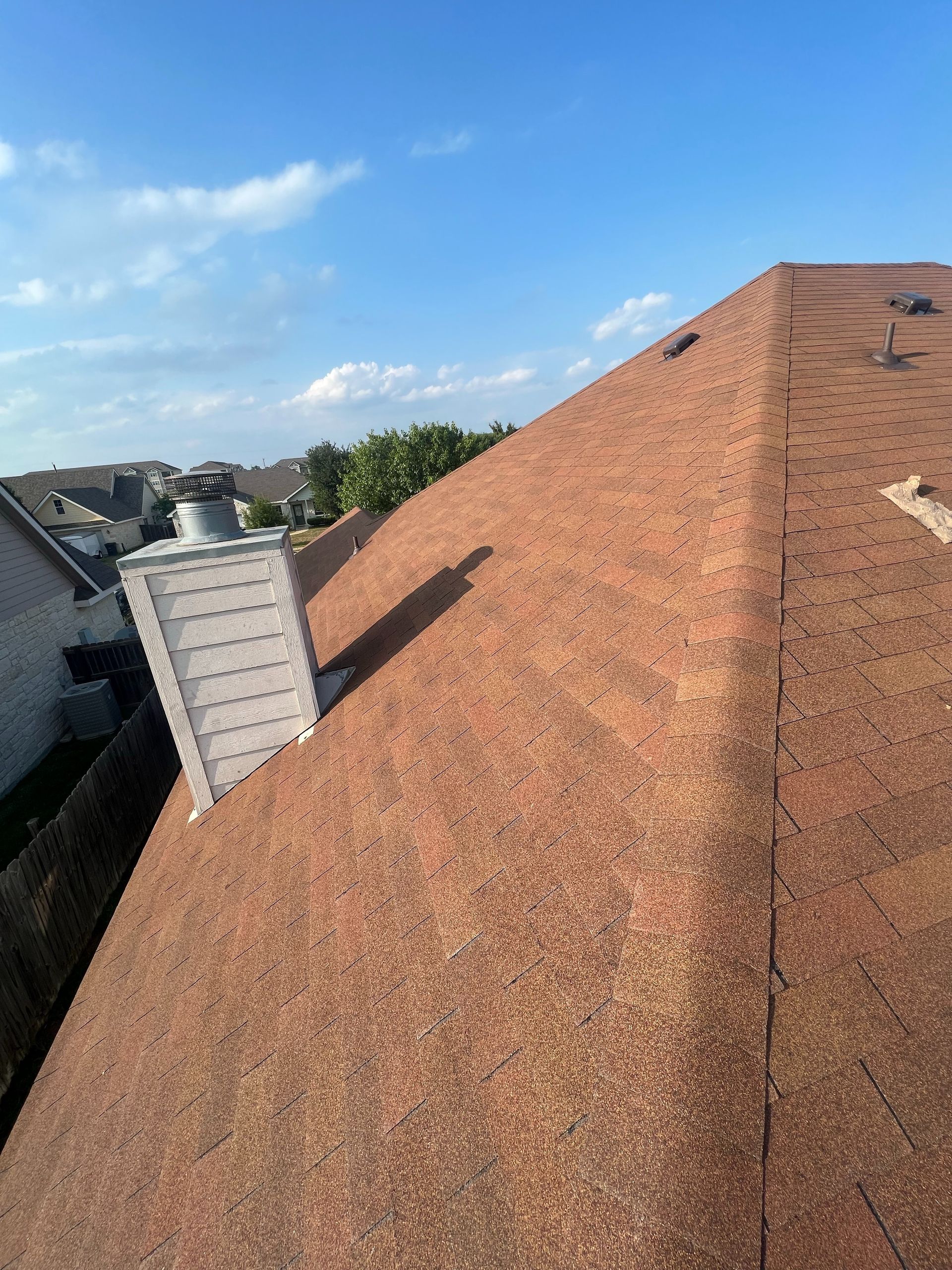 A roof with a chimney on it and a blue sky in the background.