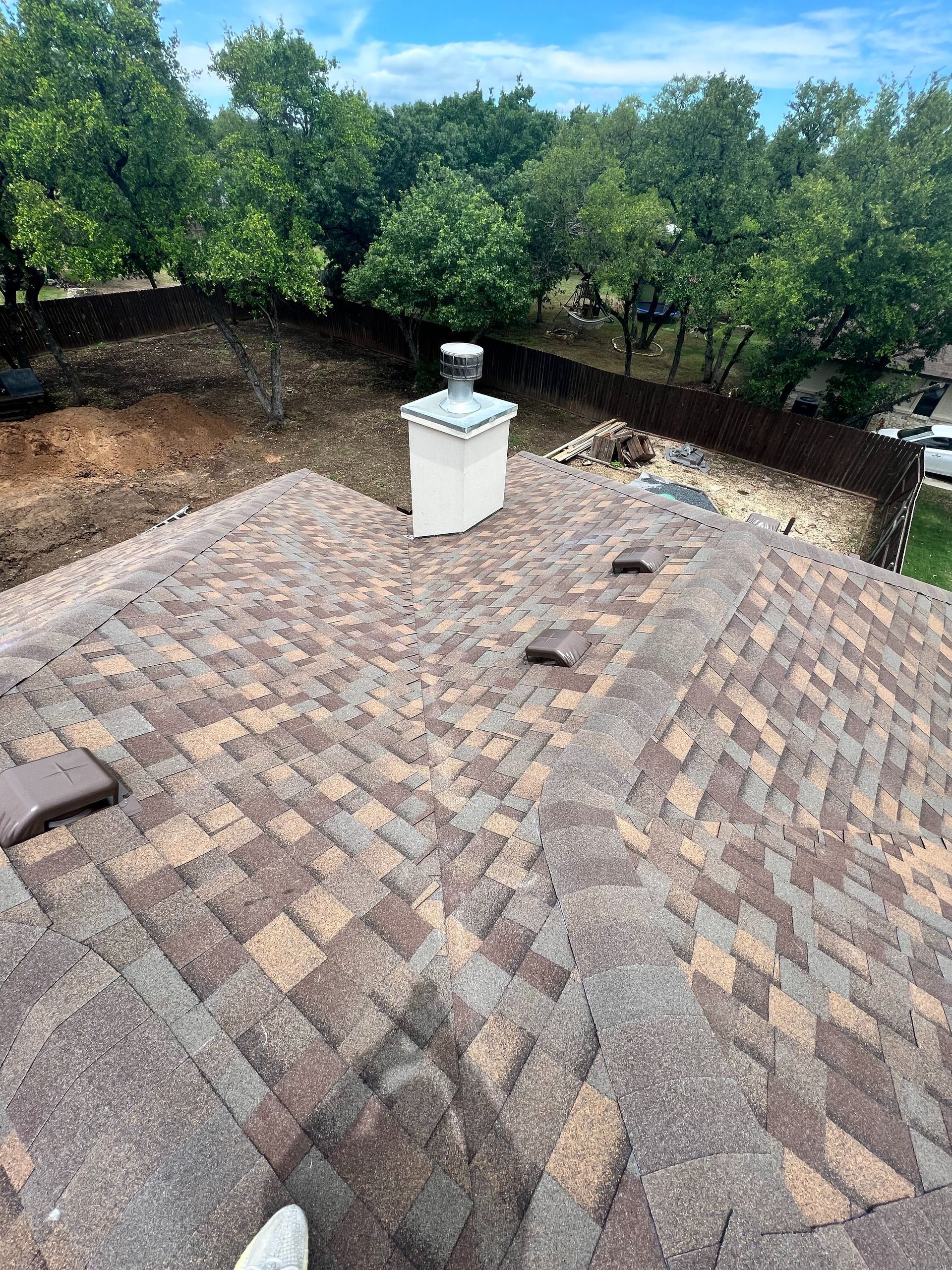 A roof with a chimney on top of it and trees in the background.