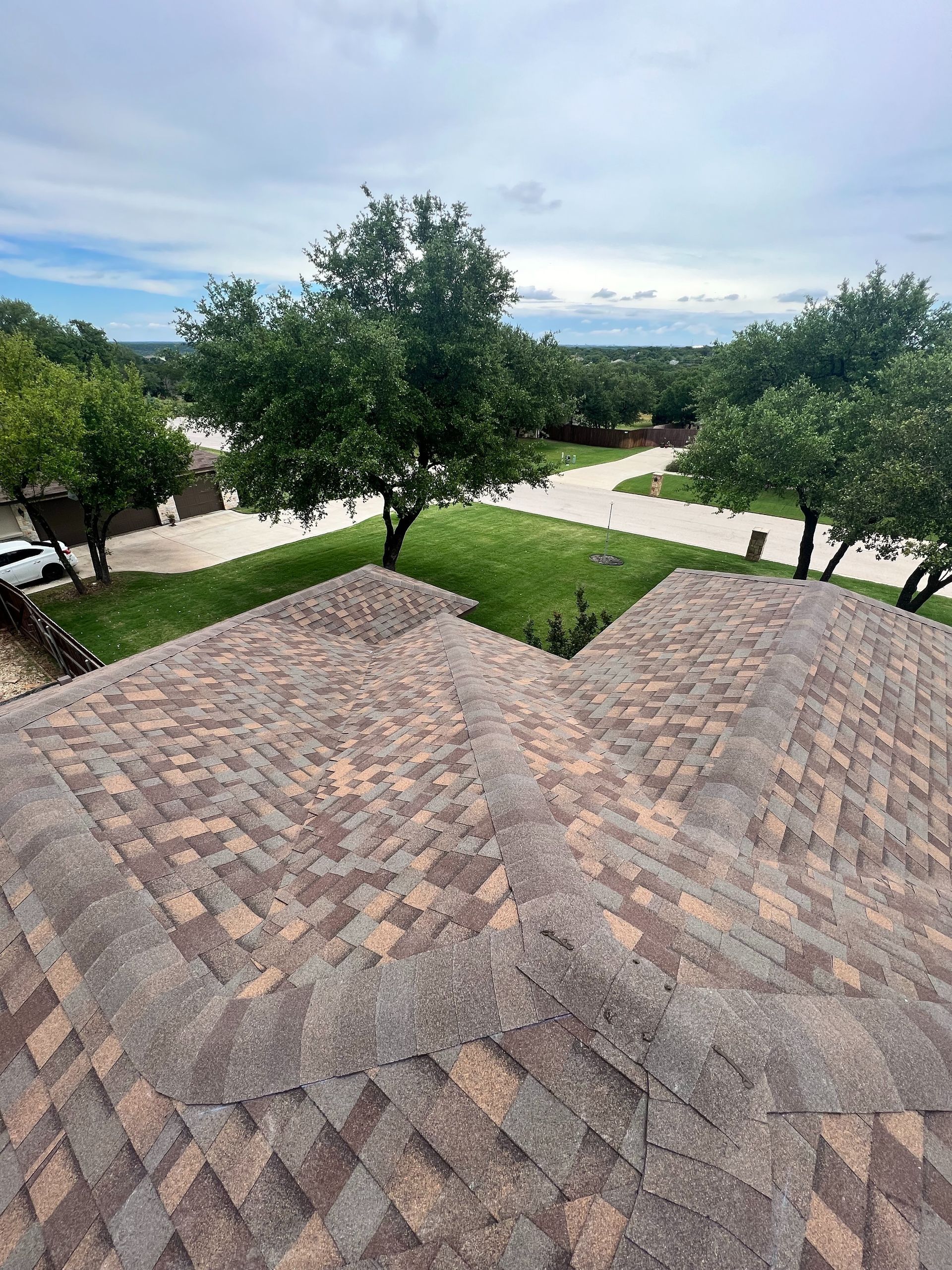 An aerial view of a roof of a house with trees in the background.