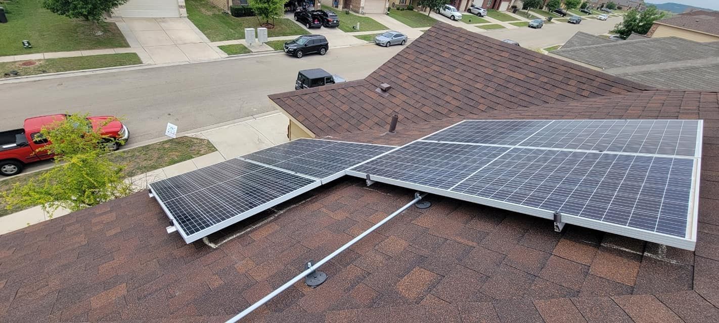 There are many solar panels on the roof of a house.