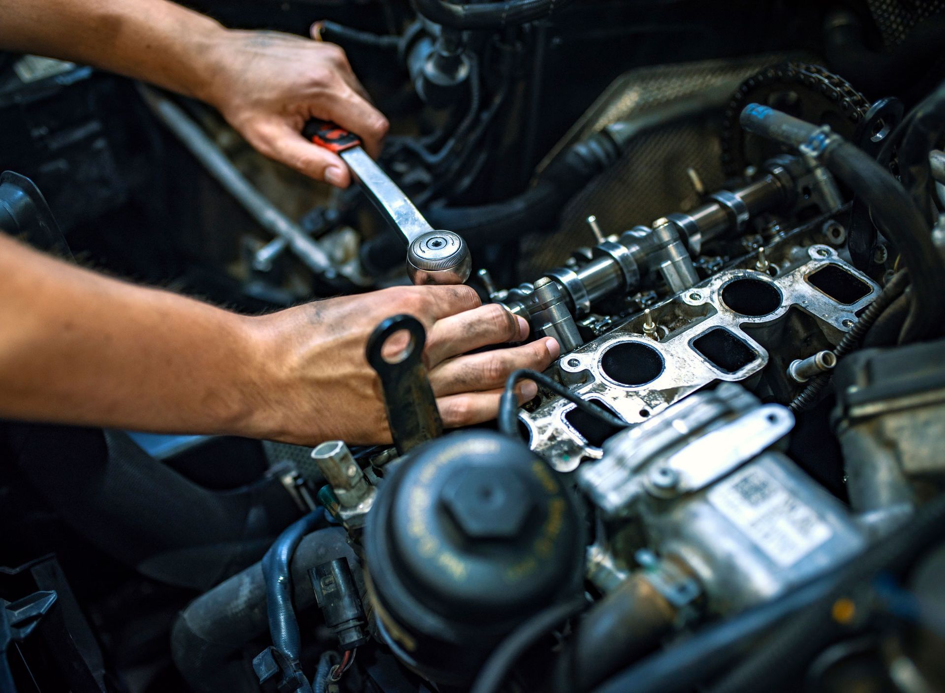 Mechanic working on a car engine with a wrench. Close-up of hands and engine components.