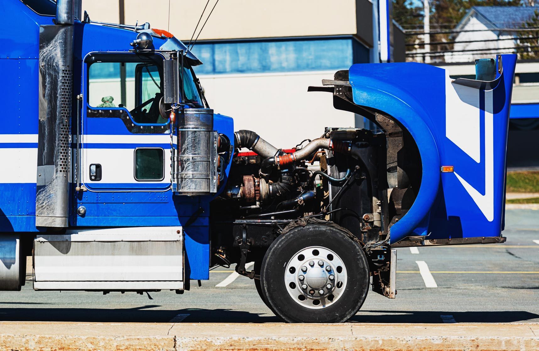 Blue semi-truck with hood open, parked in a lot, revealing the engine.