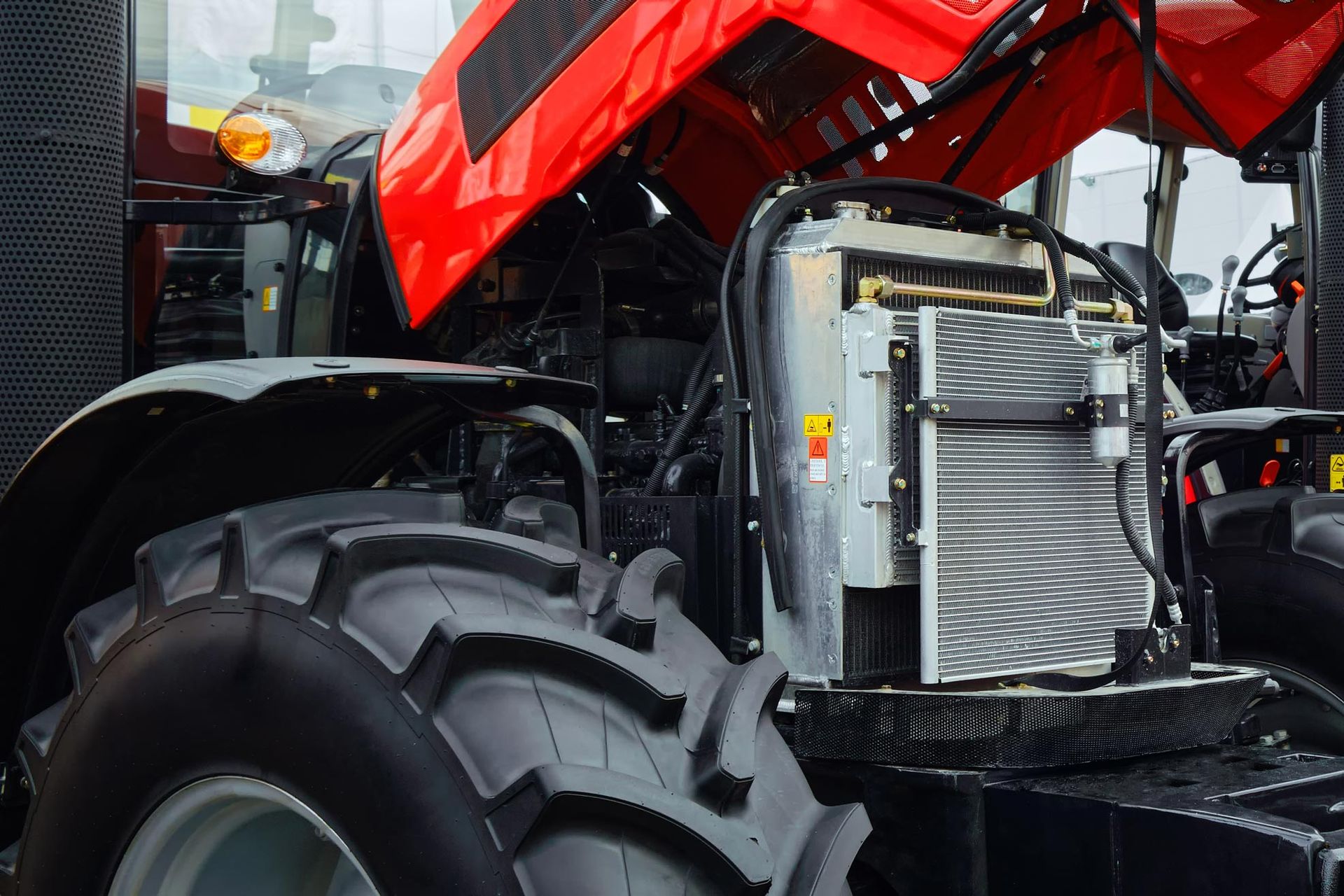 Red tractor with the hood open, revealing the engine. Front view, daylight.