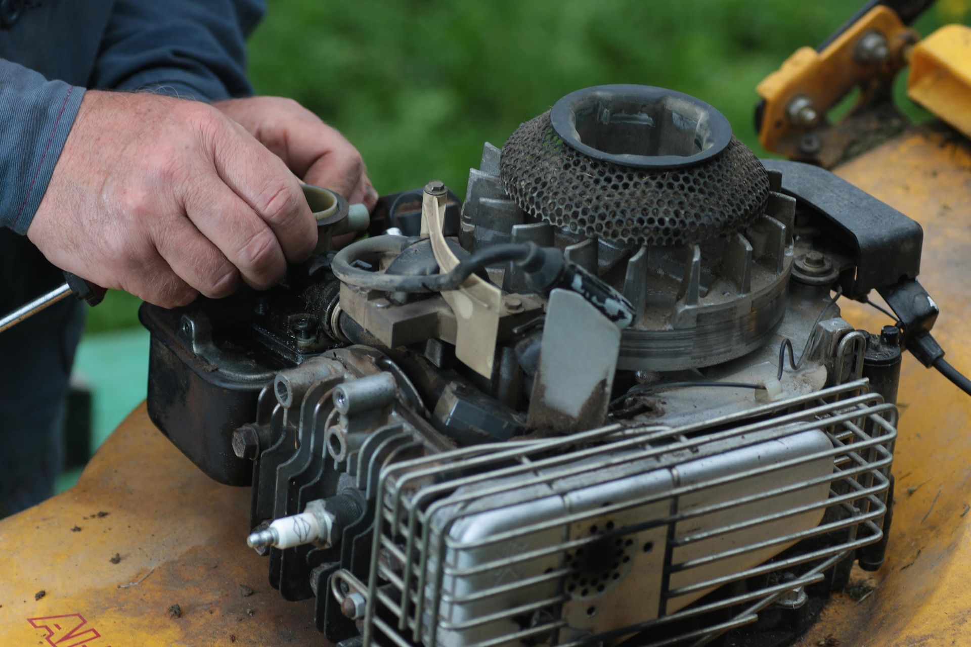Hands working on the engine of a lawn mower.